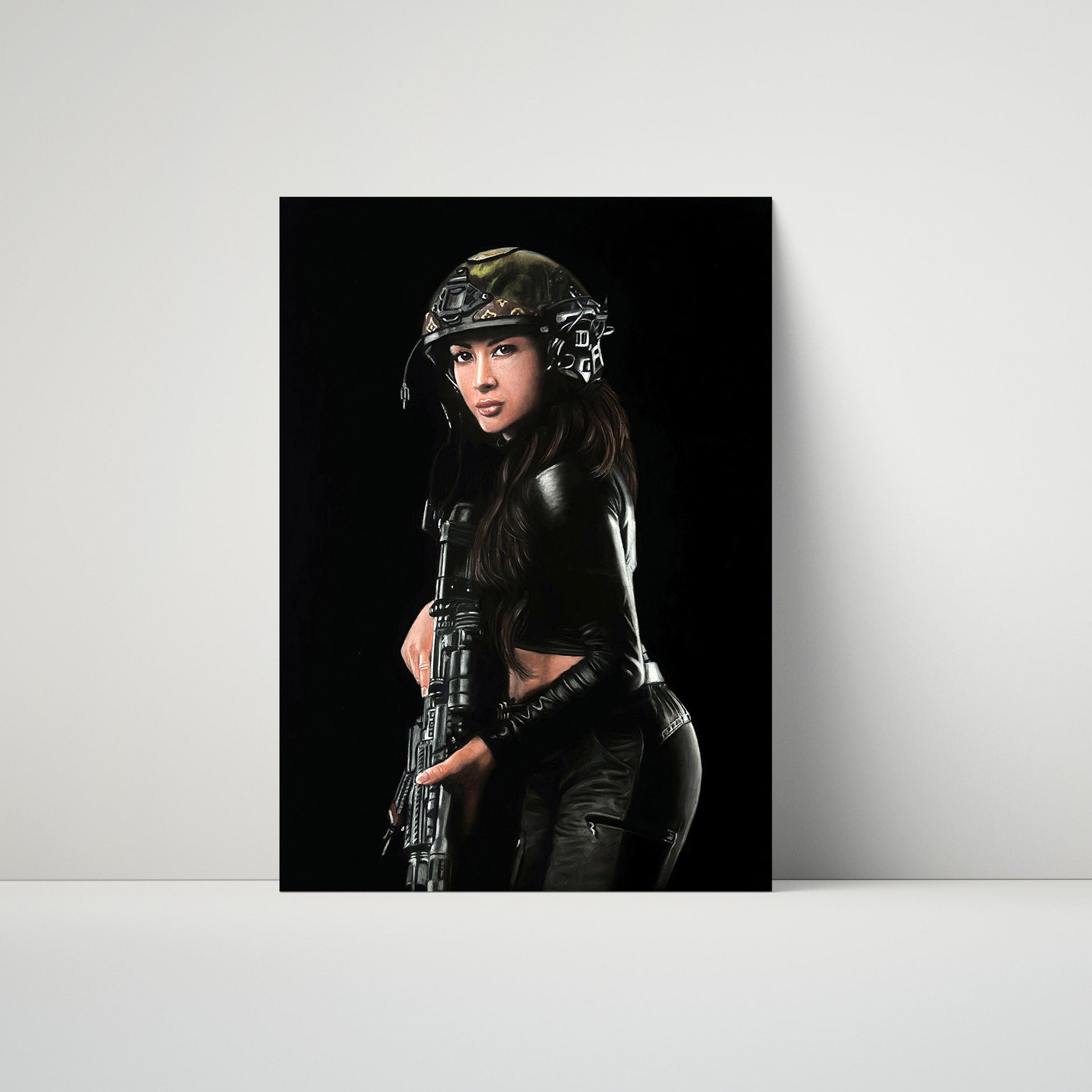 A vertical art print or poster leaning against a light gray wall on a white surface. The print shows a woman in tactical gear and a helmet holding a rifle against a black background.