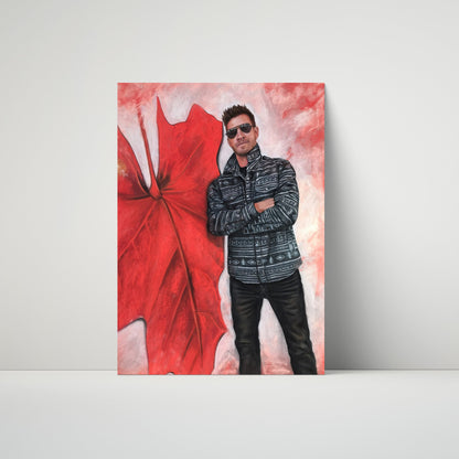 A vertical canvas art print leaning against a light gray wall on a white surface. The artwork features a stylized portrait of a man wearing sunglasses and a patterned jacket next to a large red maple leaf on a pink and white textured background.