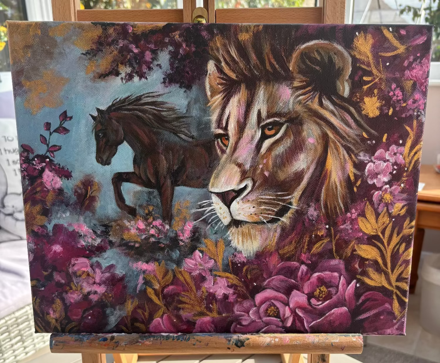 Painting of a lion and horse on an easel outdoors